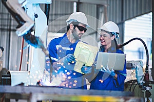 Two engineers mechanic using computer controller Robotic arm for welding steel in steel factory workshop. Industry robot