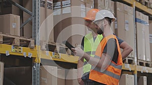 Two Engineers in a modern warehouse. Two people in the warehouse are discussing something.