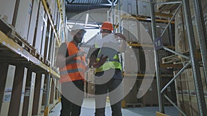 Two Engineers in a modern warehouse. Two people in the warehouse are discussing something.