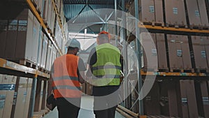 Two Engineers in a modern warehouse. Two people in the warehouse are discussing something.