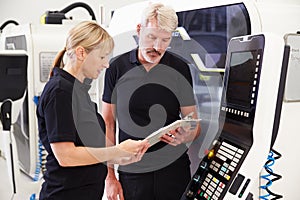 Two Engineers Operating CNC Machinery On Factory Floor