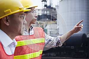 Two engineers in protective workwear pointing outside of a factory