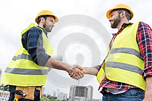 two engineers in safety vests and helmets shaking hands