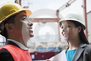 Two engineers smiling in protective workwear outside in a shipping yard photo