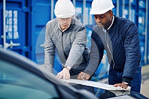 Two engineers standing in a commercial shipping yard discussing