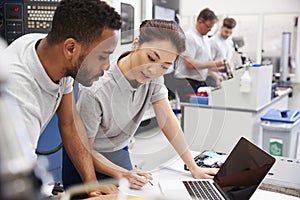 Two Engineers Using CAD Programming Software On Laptop