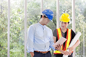 Two engineers working meeting room with a tablet. Two workers are watching construction plan. at the office. Electricians carpente