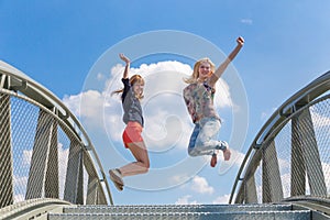 Two enthusiastic girls jumping on bridge