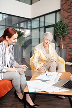 Two enthusiastic modern businesswomen discussing business matters indoors