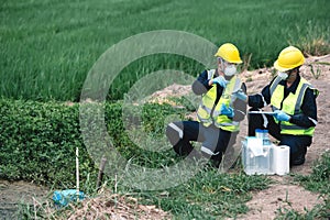 Two Environmental Engineers Inspect Water Quality and Take Water Samples Notes in The Field Near Farmland, Natural Water Sources