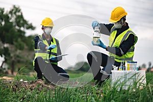 Two Environmental Engineers Inspect Water Quality and Take Water Samples Notes in The Field Near Farmland, Natural Water Sources