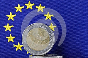 A two-euro coin and a blue flag of Europe