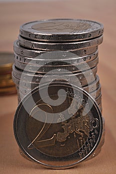 Two euro coin leaning against a stack of coins close-up