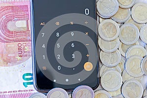 Two-euro coins, a 10-euro bill, and cell phone with calculator