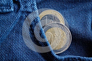 Two Euro coins with a denomination of 1 and 2 euro in the pocket of blue denim jeans