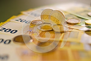 two euro coins and Two hundred euro banknotes .Expenses and incomes in European countries. Finance and savings.Cash