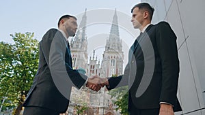 Two european businessmen shaking hands partnership deal business while standing outside on the street in the morning