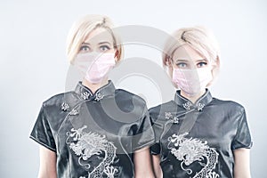 Two European-looking women are dressed in black Chinese dresses and medical face masks. blonde girls do not keep a safe distance