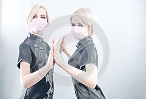 Two European-looking women are dressed in black Chinese dresses and medical face masks. blonde girls do not keep a safe distance