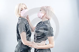 Two European-looking women are dressed in black Chinese dresses and medical face masks. blonde girls do not keep a safe distance