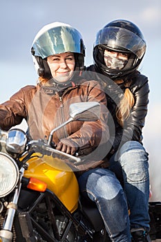 Two European women driving together on one bike, passenger sitting behind driver