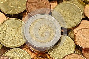 Two Euros coin on top of a pile of other coins