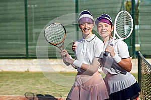 Two excited caucasian women on court. Women in sports uniform with tennis racket