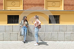 Two excited happy hipster cool women walking together on the street. High Fashion amazed model woman posing in city street. Happy