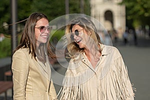 Two excited happy women walking together on the street. High Fashion amazed model woman posing in city street. Happy