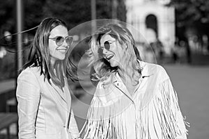 Two excited happy women walking together on the street. High Fashion amazed model woman posing in city street. Happy