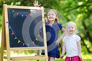 Two excited little sisters by a chalkboard