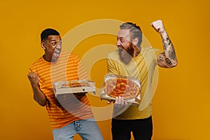 Two excited men screaming and gesturing with thrill holding pizza while standing isolated