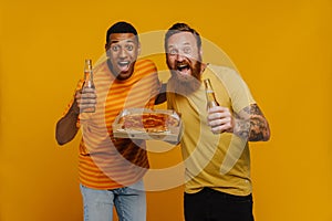 Two excited men screaming with thrill holding pizza and beer