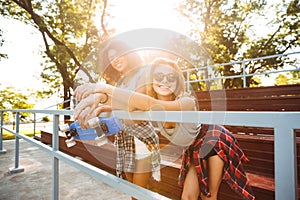 Two excited young girls with skateboard having fun together