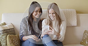 Two excited young woman reading an sms