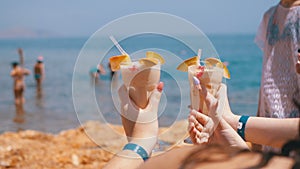 Two exotic cocktails in the hands of girls at the background of the sea and beach in Egypt.