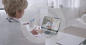 Two experienced medical specialists are exchanging knowledge and experience, chatting online by video call in notebook