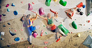 Two Experienced Rock Climbers Practicing Climbing on Bouldering Wall in a Gym. Friends Exercising at