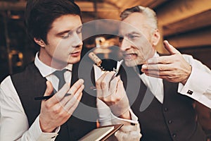 Two experienced sommeliers taste red wine and make wine list in restaurant.