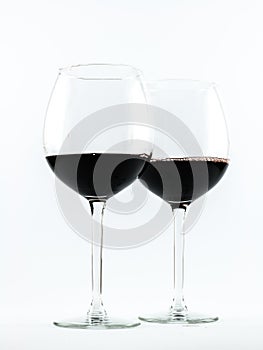 Two exquisite transparent glasses with red wine on a white background