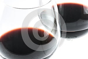 Two exquisite transparent glasses with red wine on a white background - close up