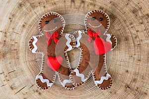 Two fabric gingerbread with hearts on wooden background, funny love story on valentines day