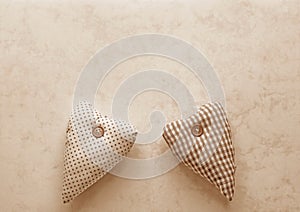 Two fabric hearts in Peach Fuzz on a paper background