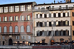 Two facades of historic buildings on the Corsini barge, with the reflection of the setting sun in the windows, in Florence.