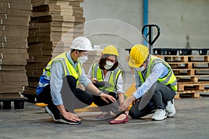 Two factory worker man help and take care coworker after accident on her leg by hydraulic cart in workplace. Concept of safety for