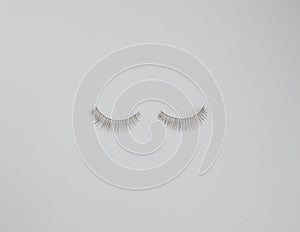 Two false eyelashes against plain white background with copy space