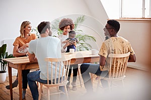 Two Families With Babies Meeting And Talking Around Table On Play Date At Home