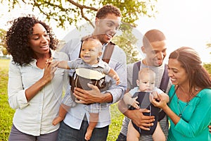 Two Families With Baby Carriers Walking In Park