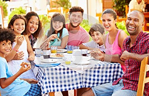Two Families Eating Meal At Outdoor Restaurant Together photo