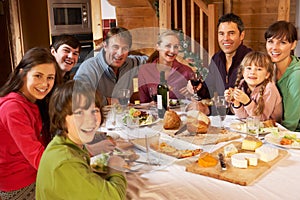 Two Families Enjoying Meal In Alpine Chalet